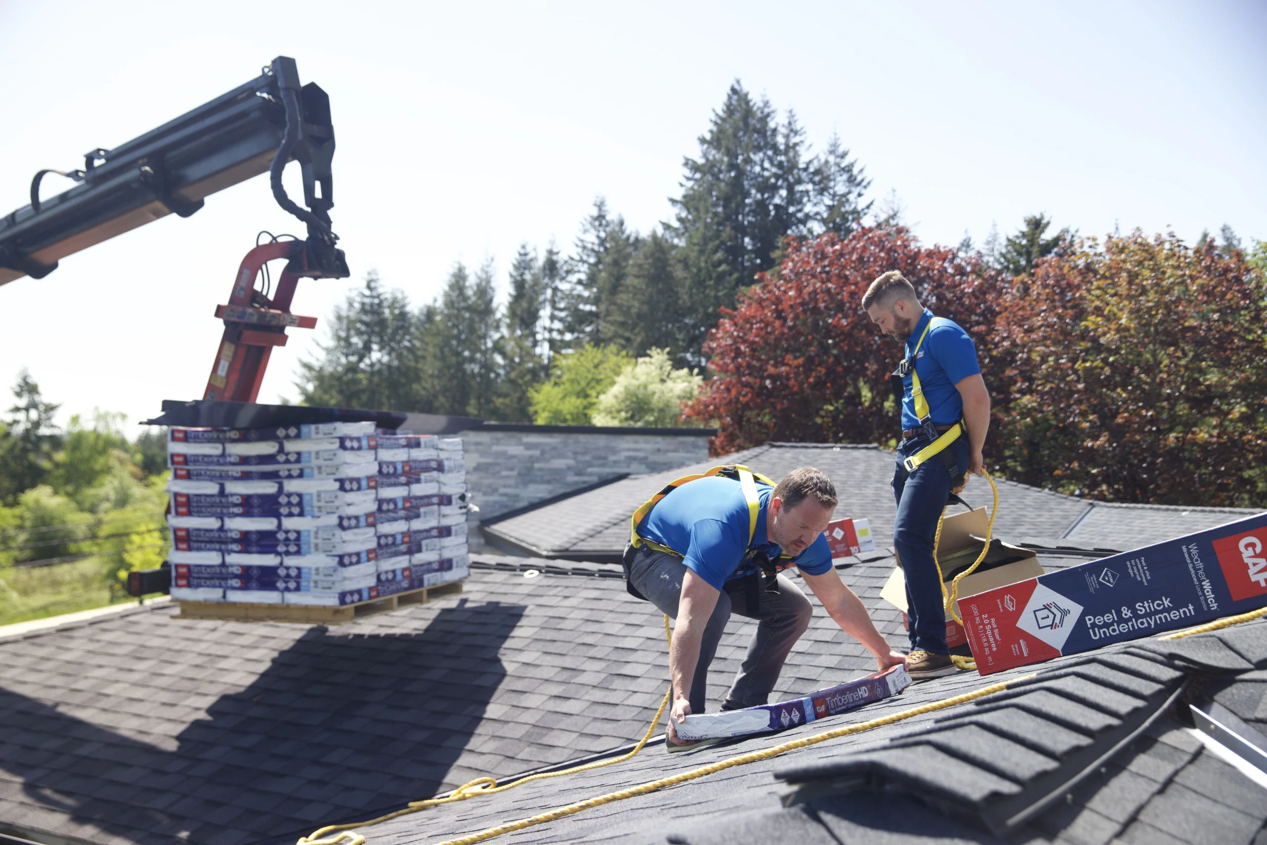 Two men unloading shingles onto a rooftop