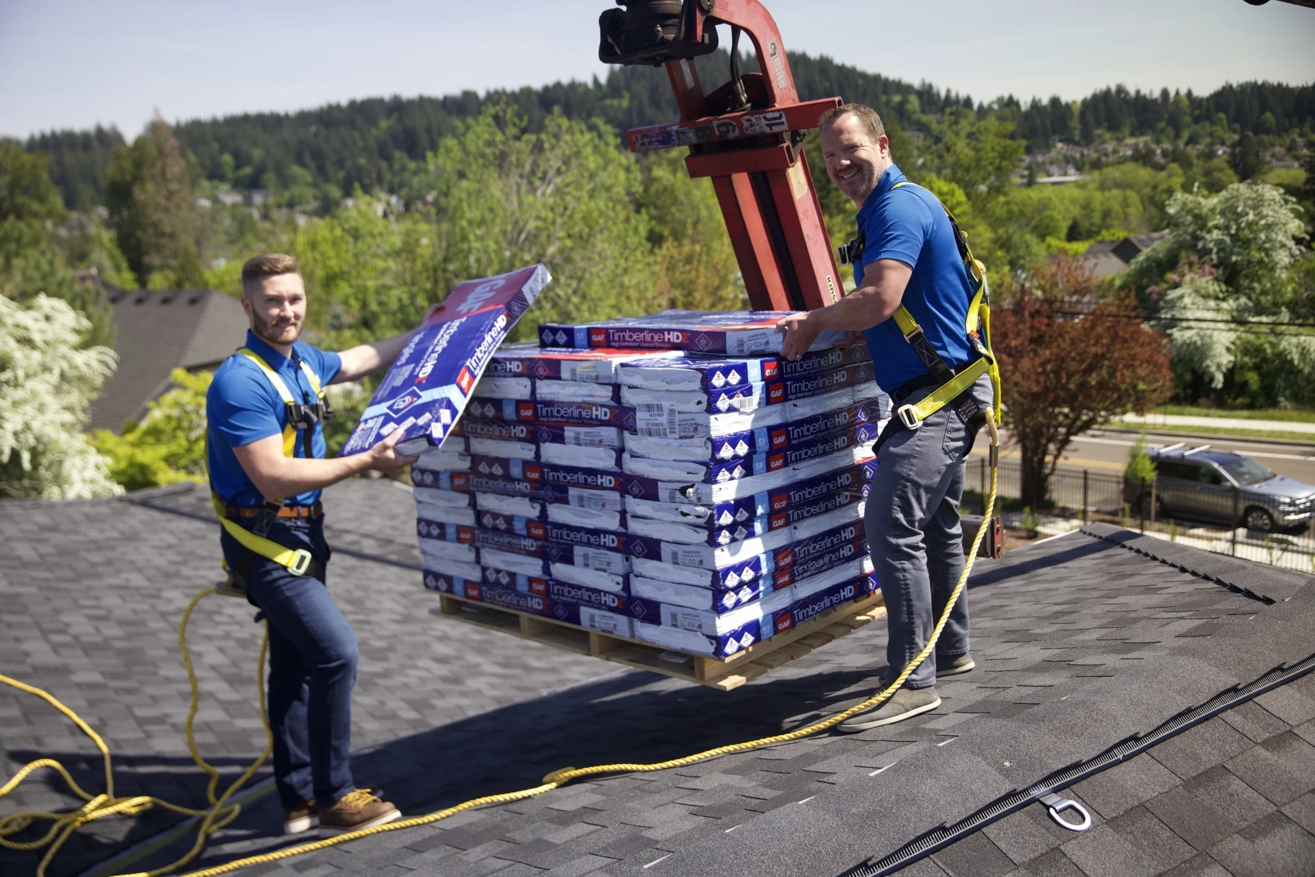 Men unloading shingles onto a rooftop.