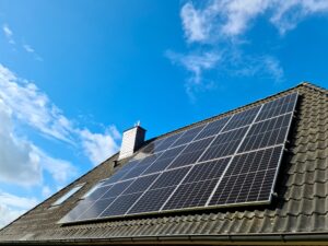 Solar panels installed on the sloped, solar-ready roof of a house under a blue sky with some clouds, demonstrating effective roof planning even for homes in cloudy climates.