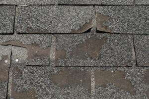 Worn and damaged asphalt roof shingles with missing granules and curled edges are shown—a clear sign Portland homeowners may need a new roof. See our homeowner’s guide for help identifying when it’s time to replace your roof.